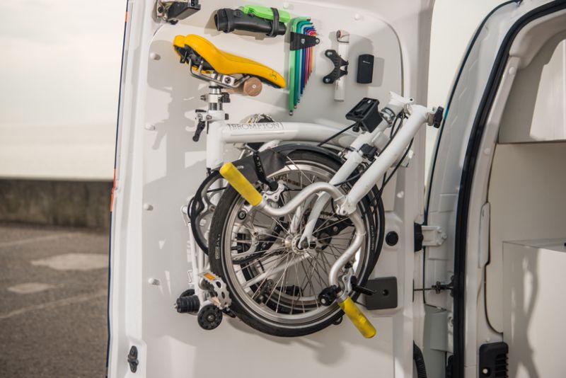 A folding Brompton bike mounts on the rear door for easy access