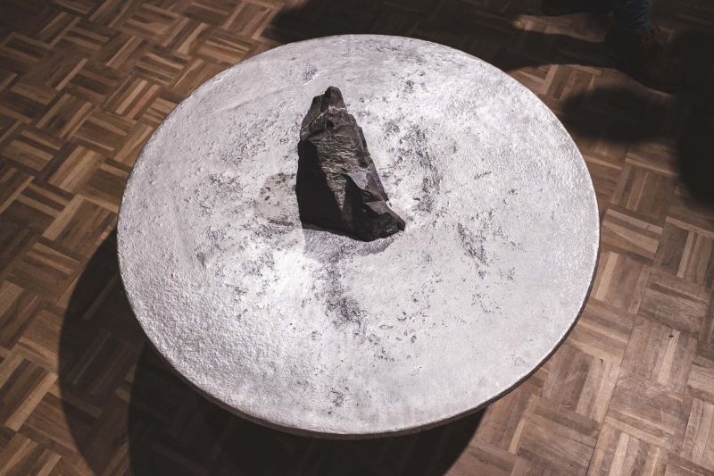 Lunar table by Jesse Ede features monotholic rock piercing through aluminum tabletop
