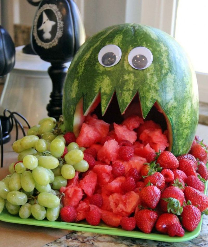 Watermelon monster with googly eyes in a fruit tray with grapes and strawberries 