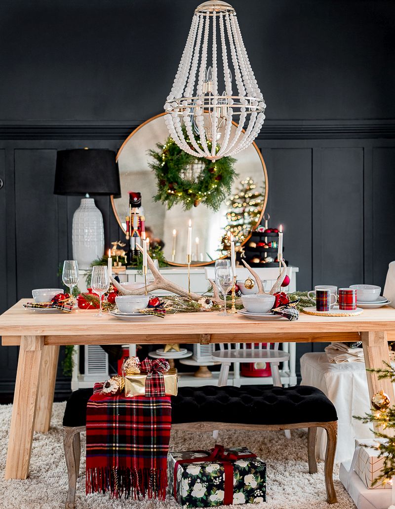 golden candle holders, red cups and an antler in the center of Christmas table