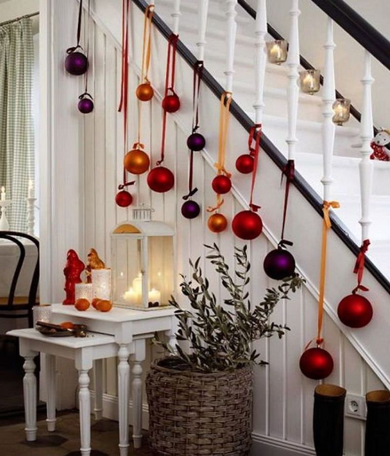 Oversized Christmas tree ornaments hanging on staircase railing 