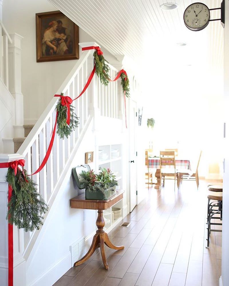 Simple staircase decor with green tree branches and red ribbon 
