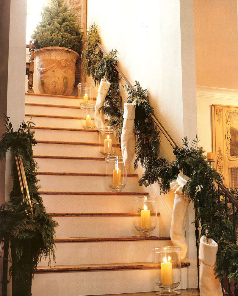 Glass candle holders, stocking and green garland on staircase 