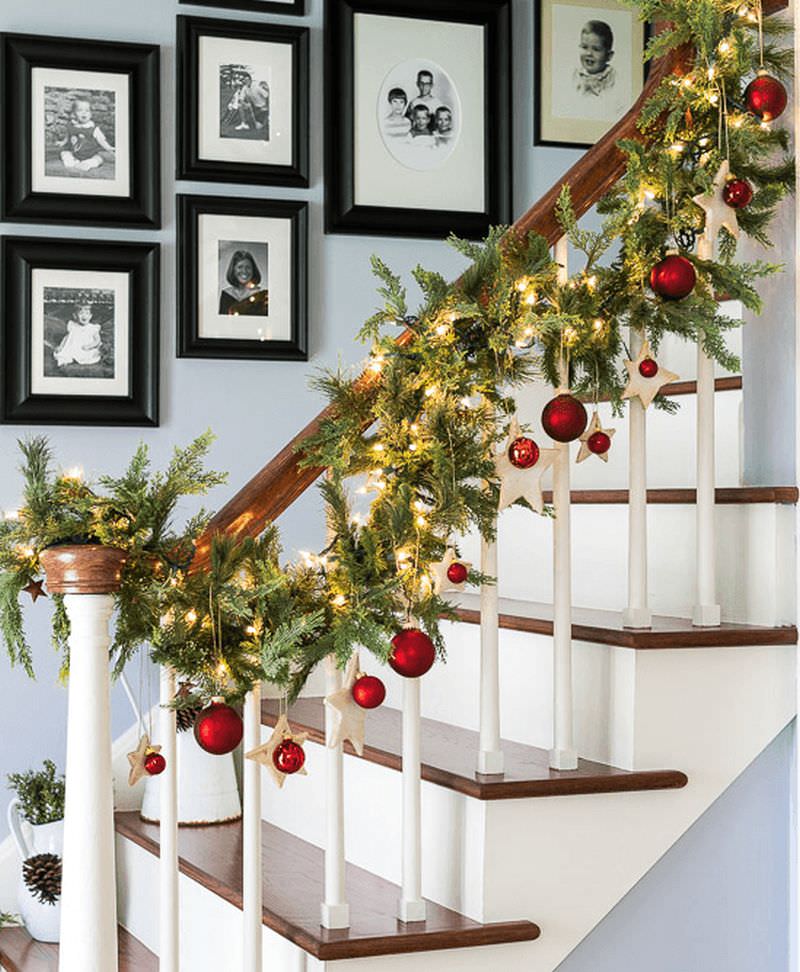 Artificial greenery, lights, stars and red balls hanging on staircase 