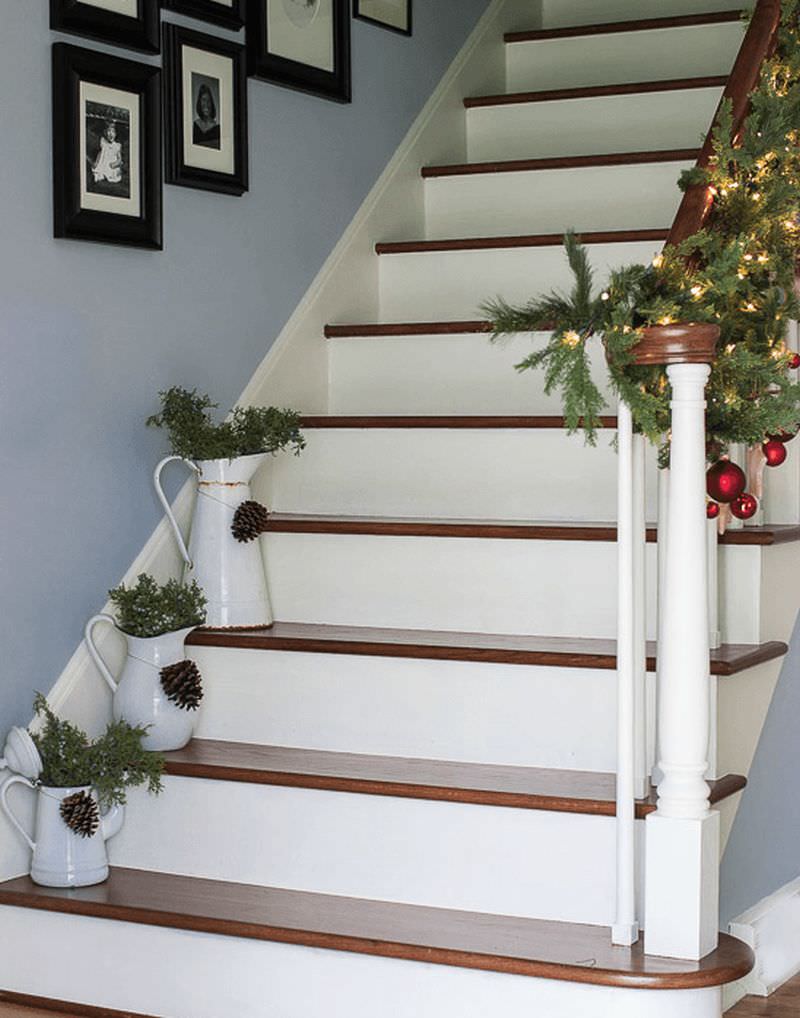 Planters with greenery and pine cones placed on white staircase steps